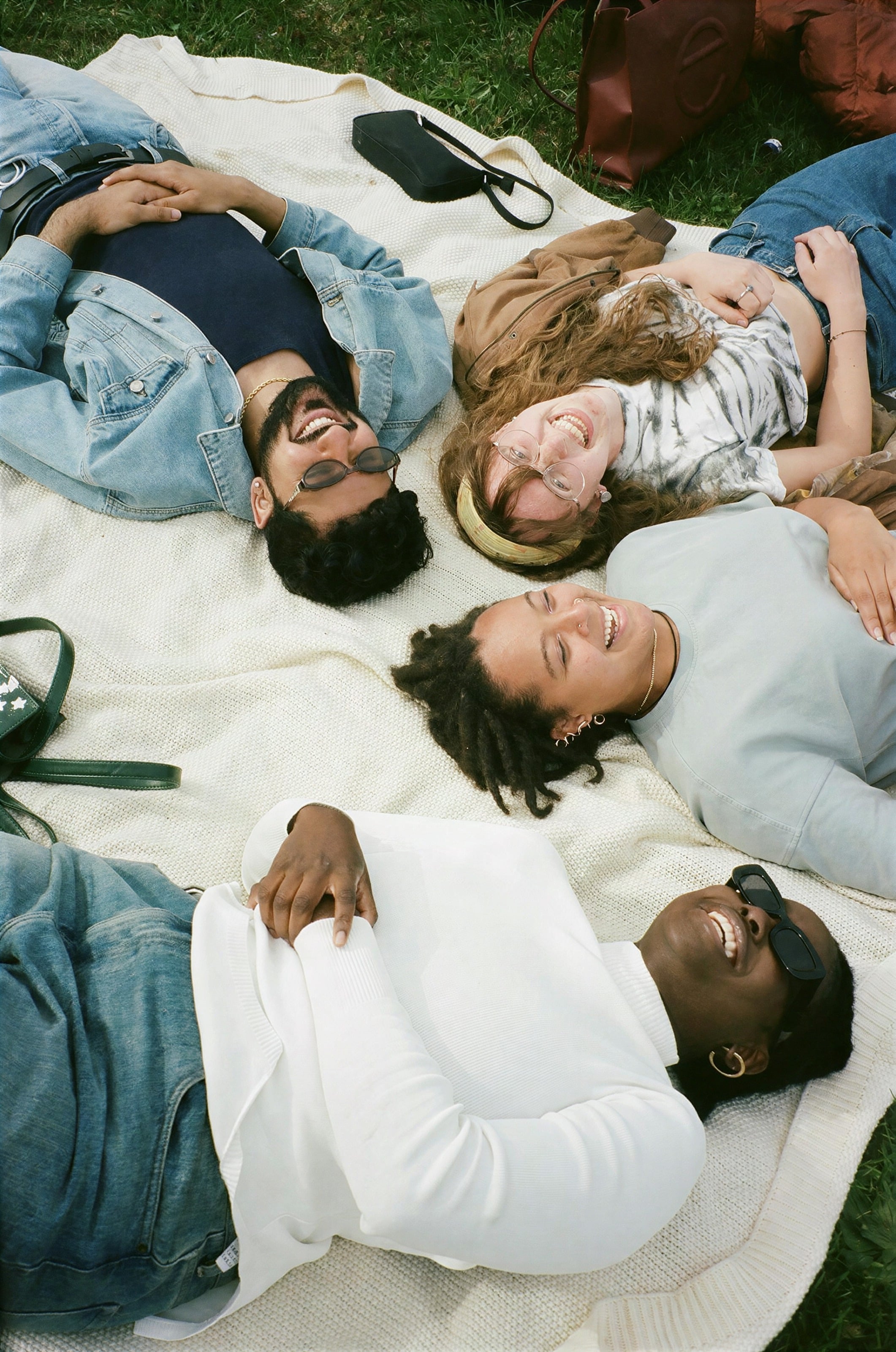 Friends lying on blankets with their heads together, laughing